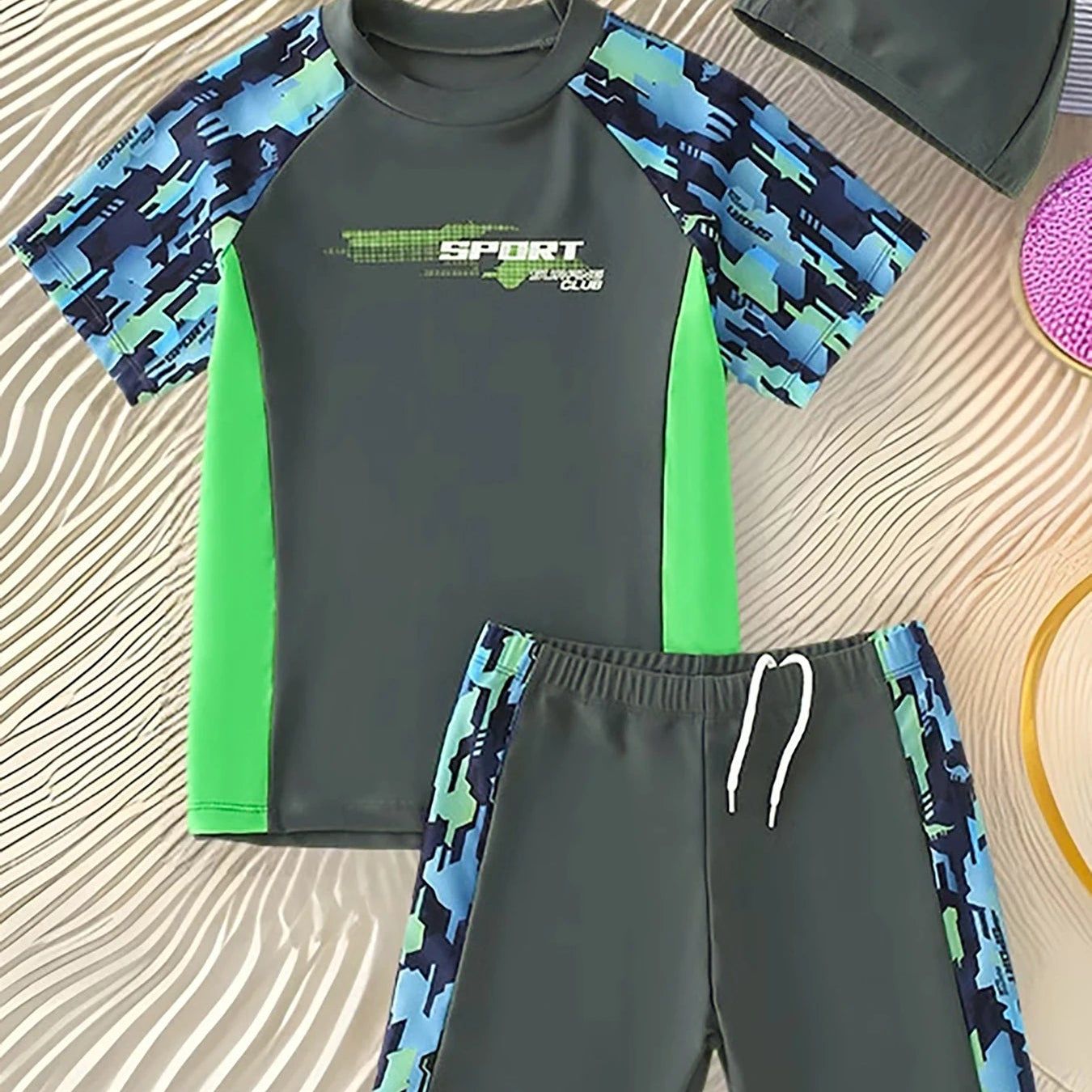 Children's swimwear set with green and blue pattern on a textured surface