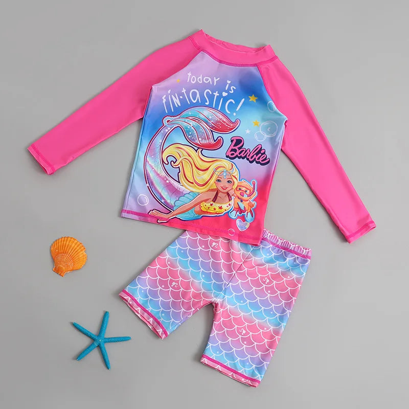 Barbie-themed children's swimsuit set with pink long-sleeve top and mermaid-patterned shorts on a gray background.