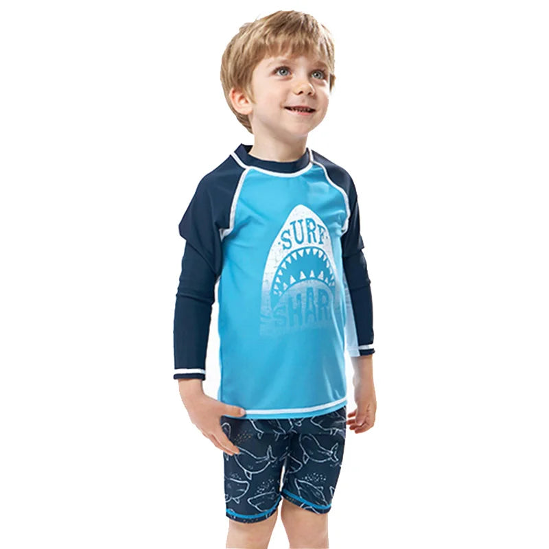 Child wearing a blue and navy shark-themed swimsuit on a white background