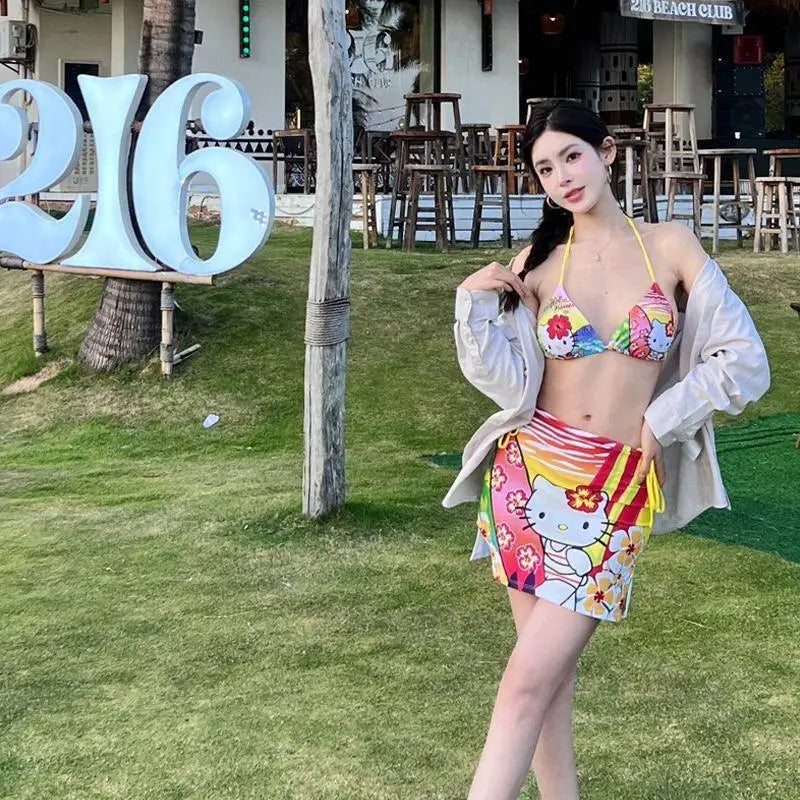 Woman in a colorful bikini and skirt standing on grass with a blurred background