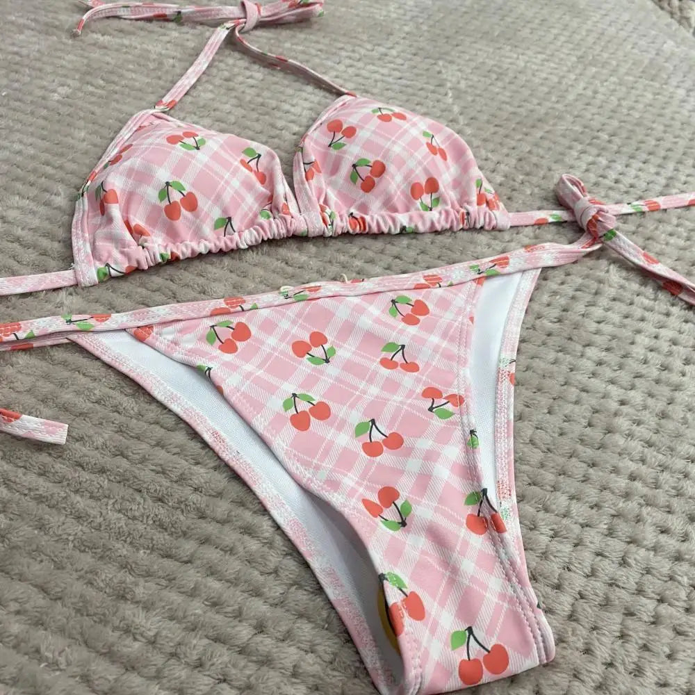 Pink bikini set with cherry pattern on a textured surface