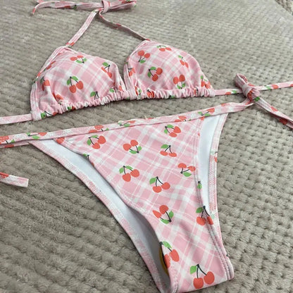 Pink bikini set with cherry pattern on a textured surface