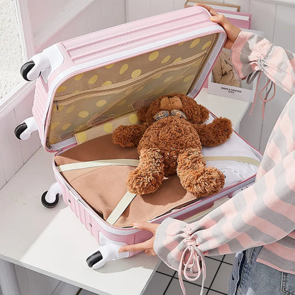 Pink suitcase with a teddy bear and other items on a white surface