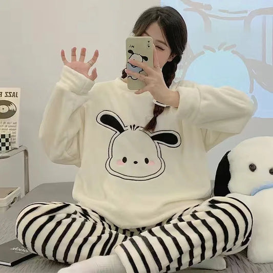 Person wearing a white hoodie with a cartoon design and striped pants, sitting on a bed.