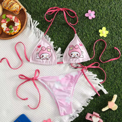Pink bikini set with cartoon character design on grass with donuts and flowers.