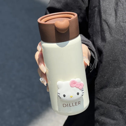 Person holding a Hello Kitty-themed tumbler with a brown lid against a dark background