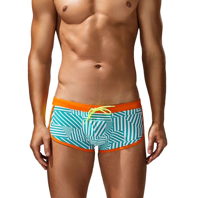 Man wearing a colorful swim trunk with geometric pattern on a white background
