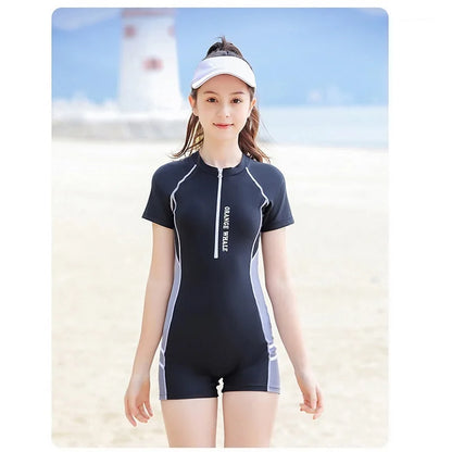 Girl wearing a black swimsuit with white accents on a beach