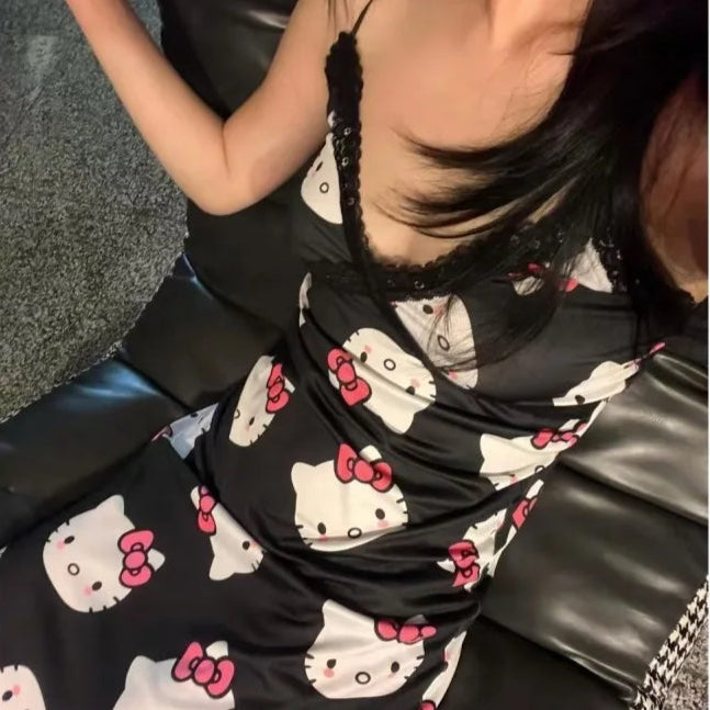 Person wearing a black dress with Hello Kitty patterns sitting on a black leather couch.