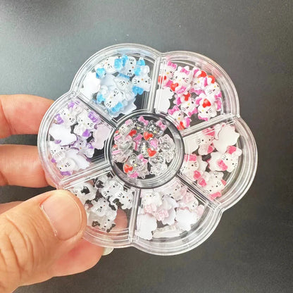 Clear plastic case with compartments filled with small decorative items, held by a hand against a dark background.