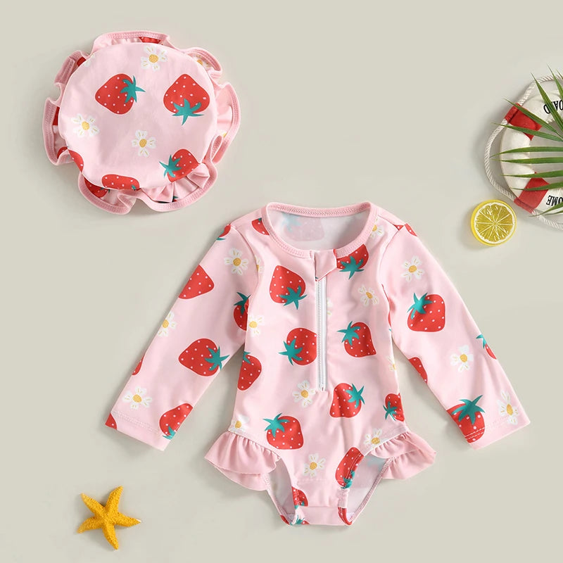 Baby swimsuit with strawberry pattern and matching cap on a light gray background