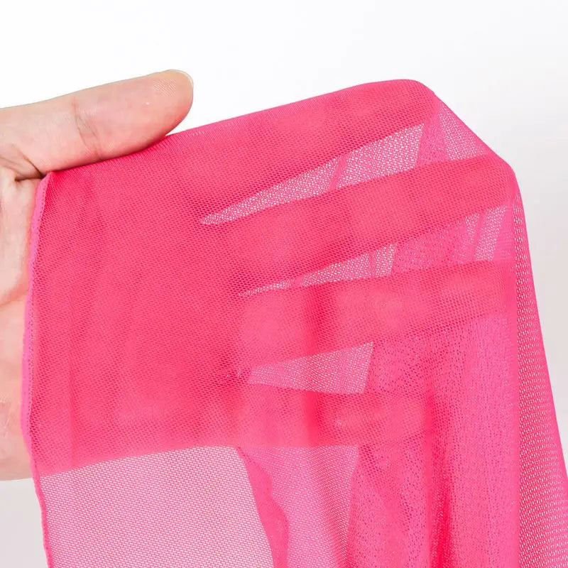 Hand holding a piece of pink netting fabric against a white background
