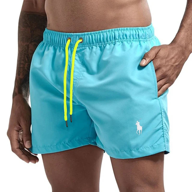 Turquoise swim shorts with yellow drawstring on a white background