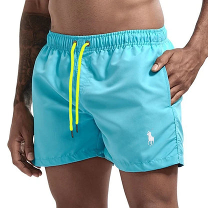 Turquoise swim shorts with yellow drawstring on a white background