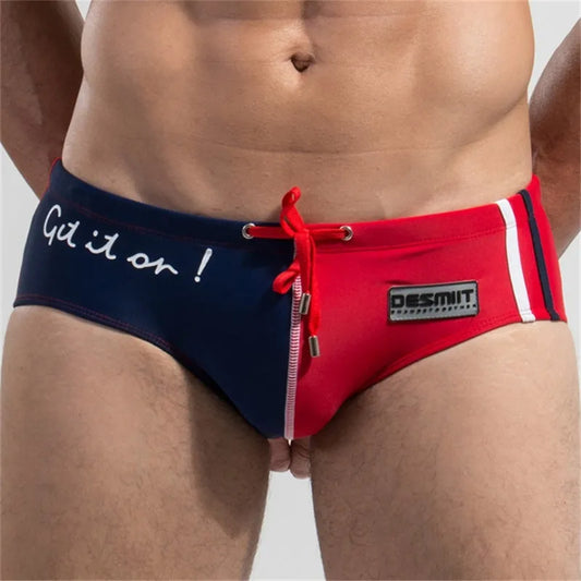 Two pairs of men's swim briefs, one navy with white text and one red with a brand logo, on a plain background.