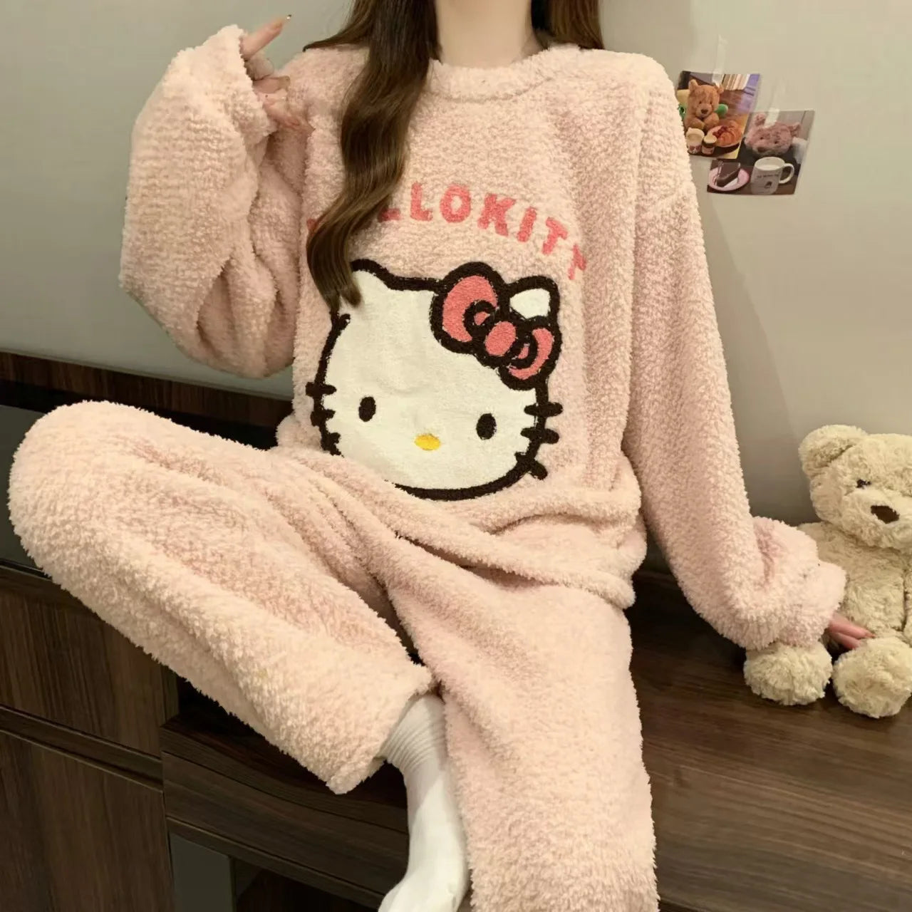 Pink Hello Kitty pajama set worn by a person sitting on a bed.