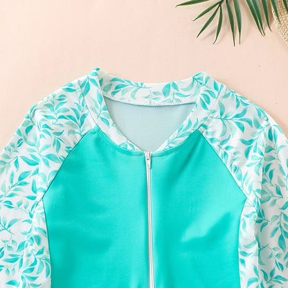 Teal swimsuit with leaf pattern on a light pink background