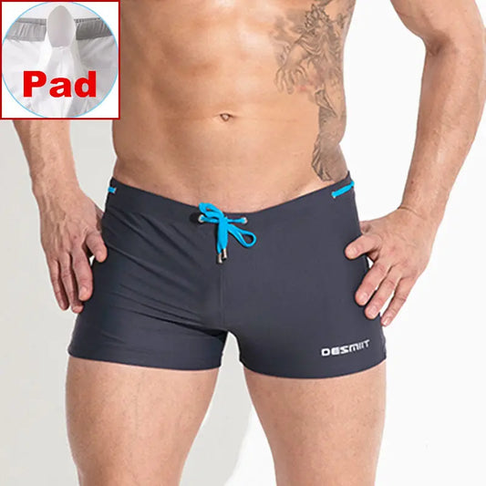 Man wearing navy swim shorts with blue drawstring,Desmit brand visible, inset showing pad area.