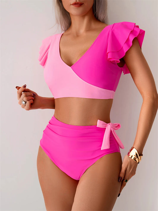 Woman wearing a bright pink bikini set with ruffled top on a plain background