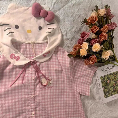 Pink checkered shirt with Hello Kitty hood and bow, next to a bouquet of flowers and a magazine.