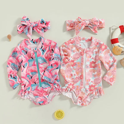 Two children's swimsuits with floral and flamingo patterns, accompanied by headbands and a lemon decoration on a light background.