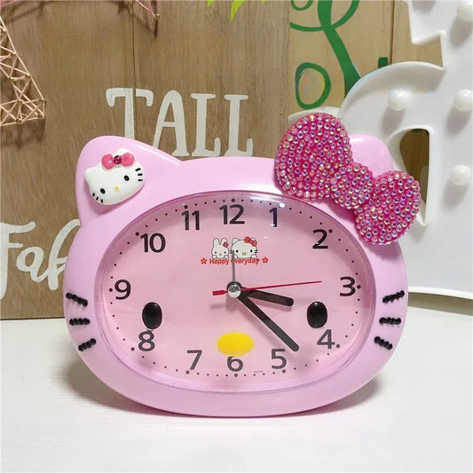 Pink Hello Kitty clock with a decorative bow on a wooden surface.