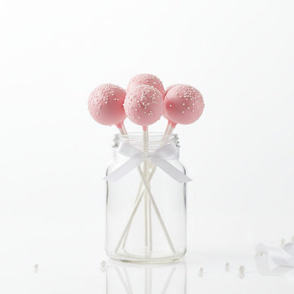 Pink cake pops with white sprinkles in a clear jar on a white background - cake pops parties.