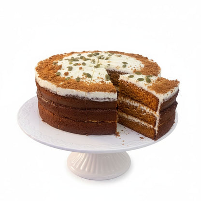 Three-layer cake with white frosting and green seeds on a white cake stand.