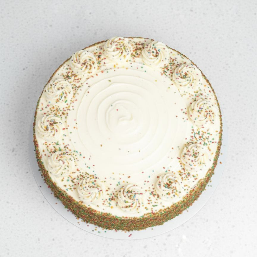Round rainbow dessert with a crumbly base and creamy top on a light gray background