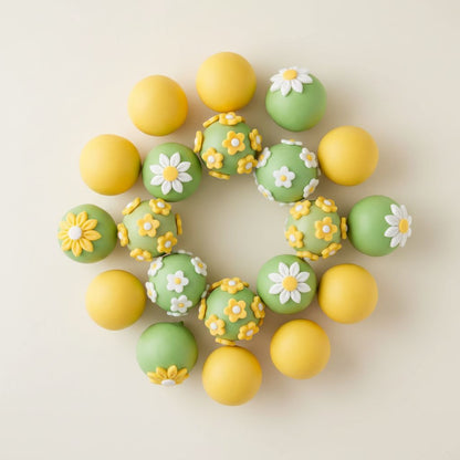 Decorative lemon-green and yellow cake pops with floral designs on a light background